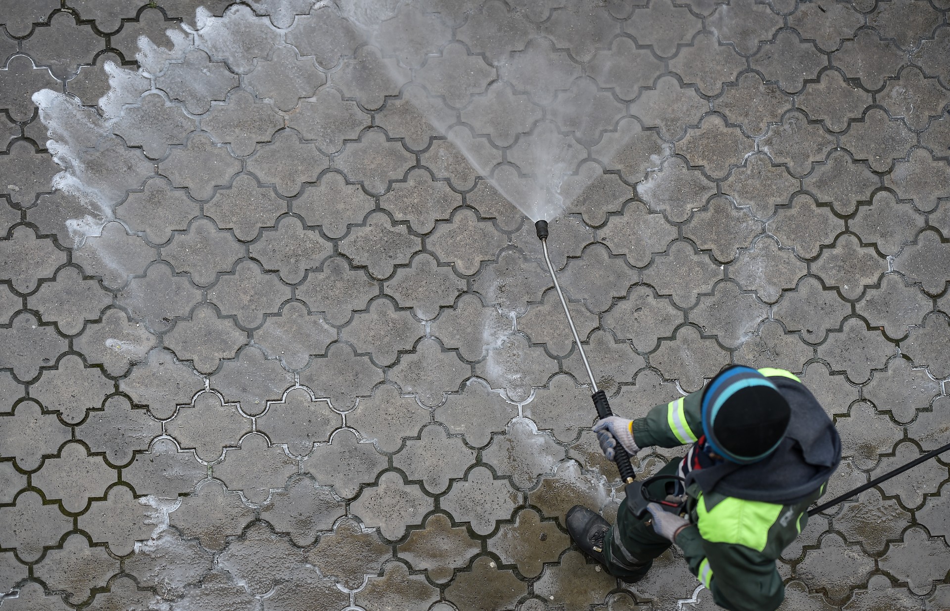 Public janitor deep cleaning the sidewalk with high pressure disinfectant solution in times of corona virus pandemic in a lockdown Bucharest, Romania